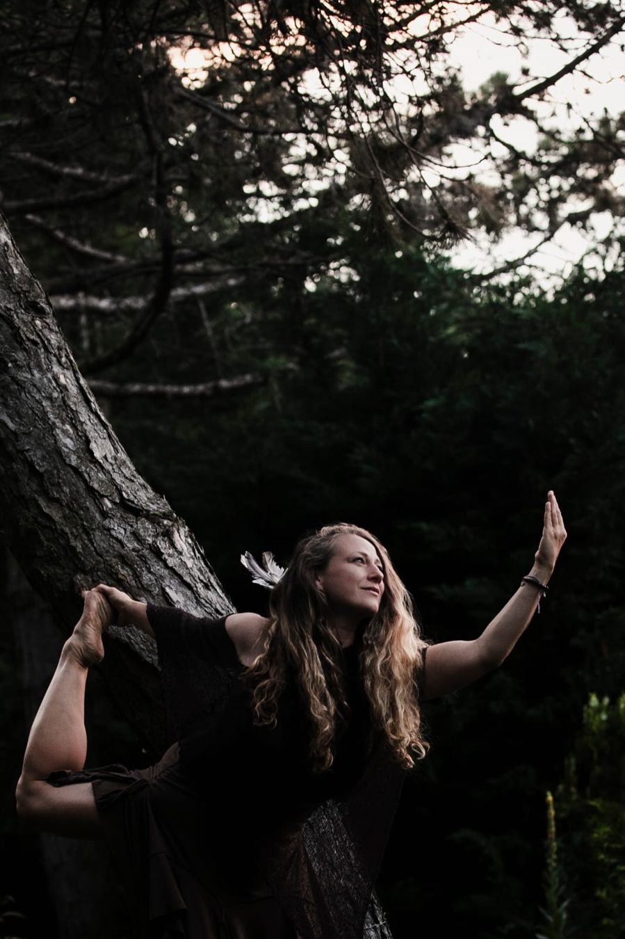 Linda Arent in einer Tanzpose an einem Baum